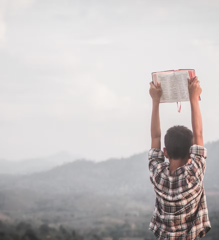 A boy holds his Bible high on a hilltop in Bulgaria
